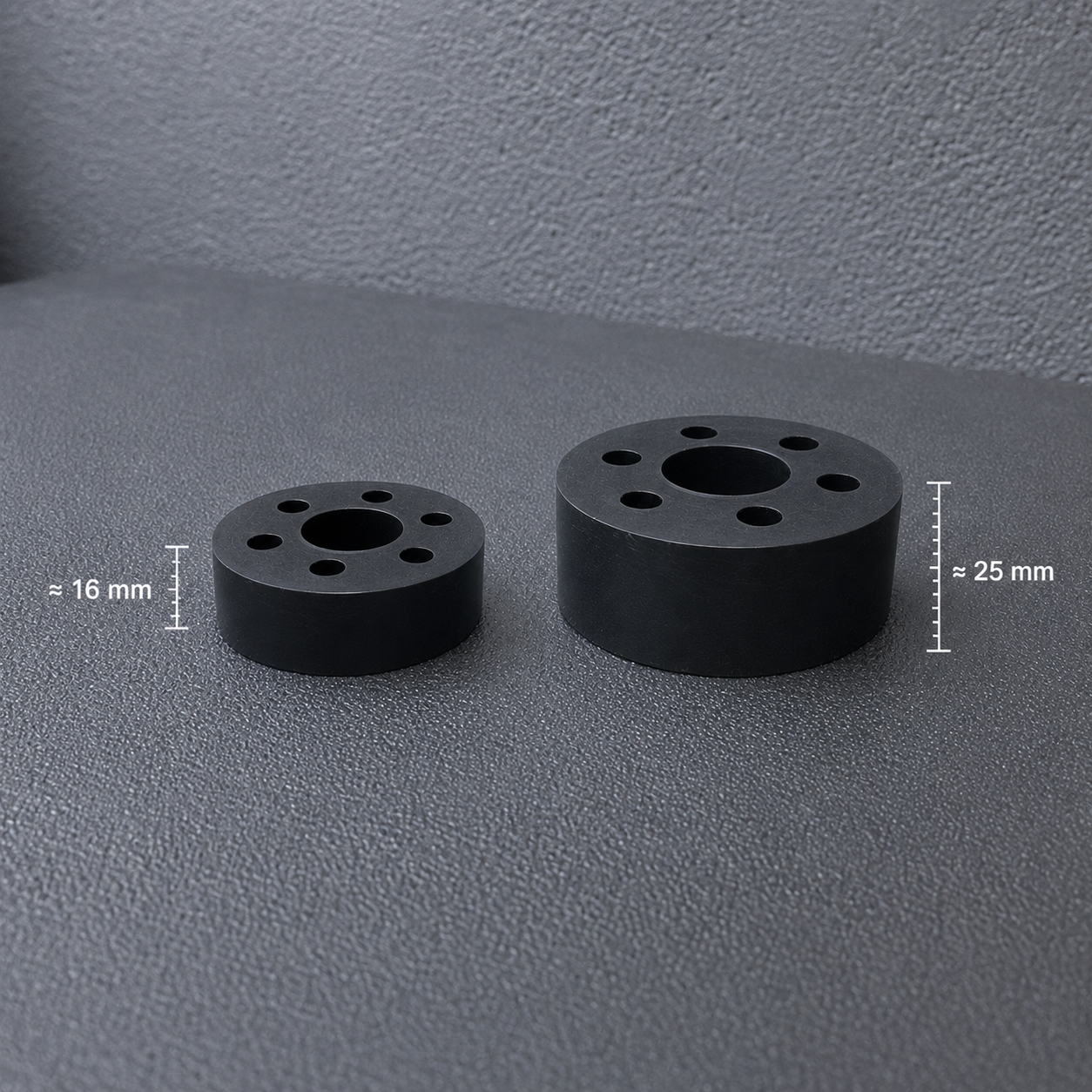 Two black circular cylindrical components with multiple holes, shown on a textured gray surface with dimension labels indicating 16 mm and 25 mm.
